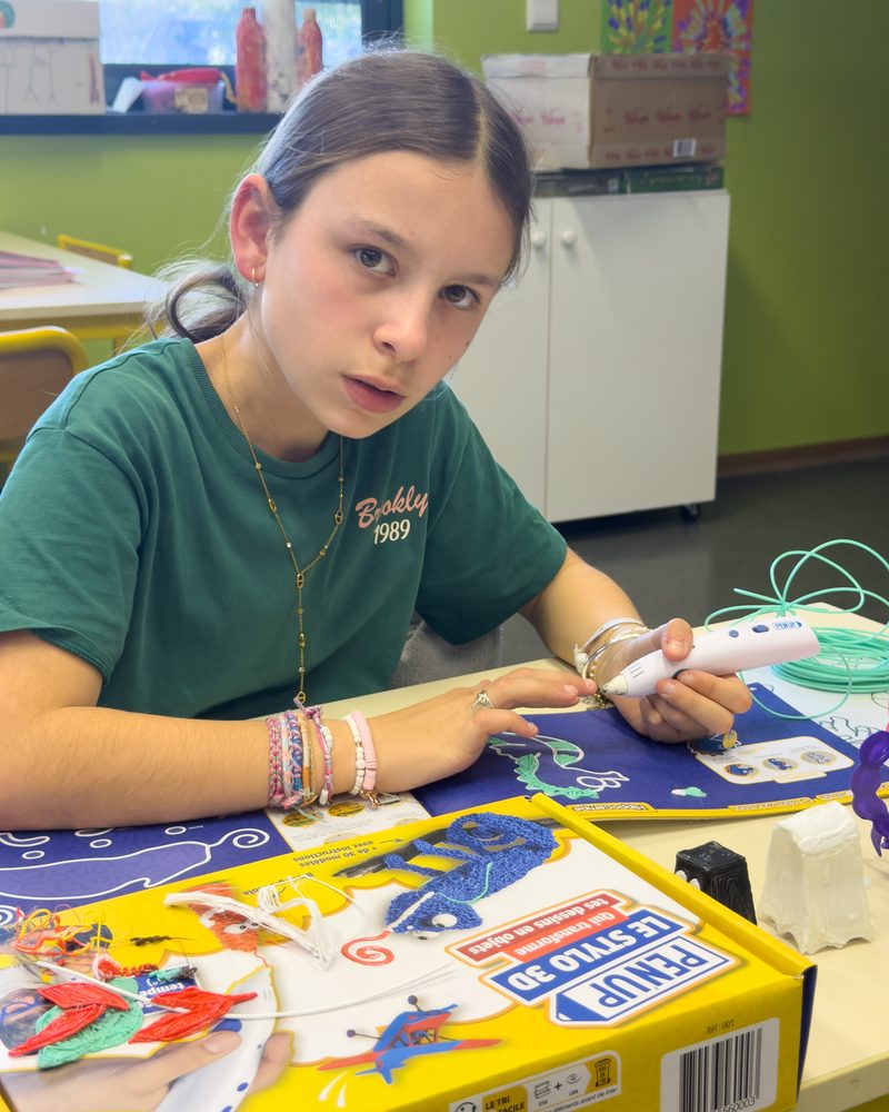 Une enfant concentrée pendant une séance de stylo 3D, le regard sur sa création