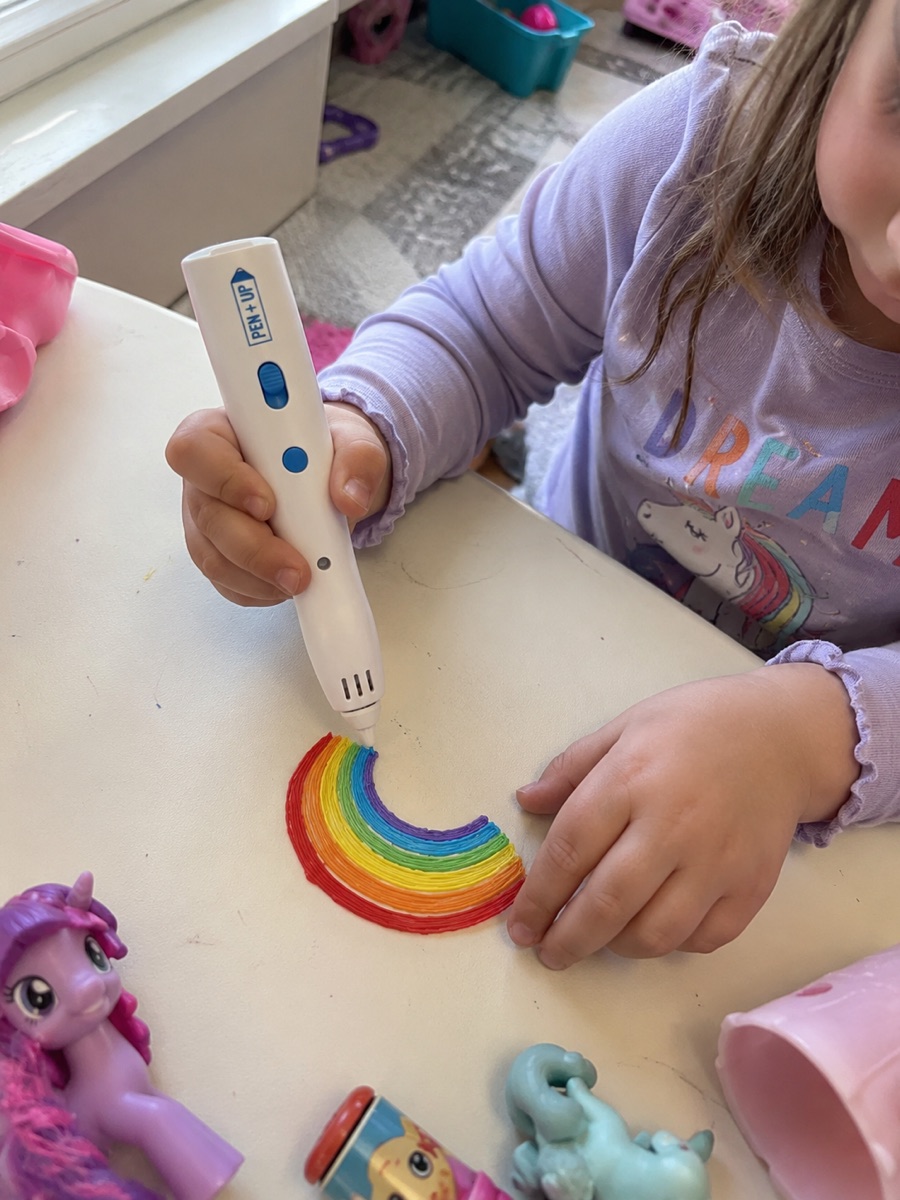 Une enfant guide lentement le stylo 3D Pen'Up 3D pour tracer sa forme