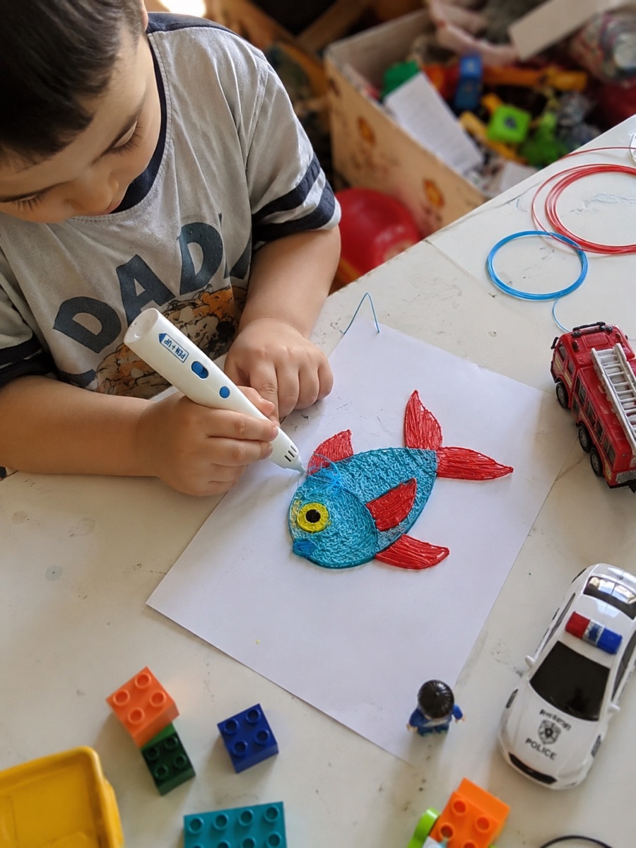 Une enfant tient le stylo 3D Pen'Up 3D et l'une de ses créations